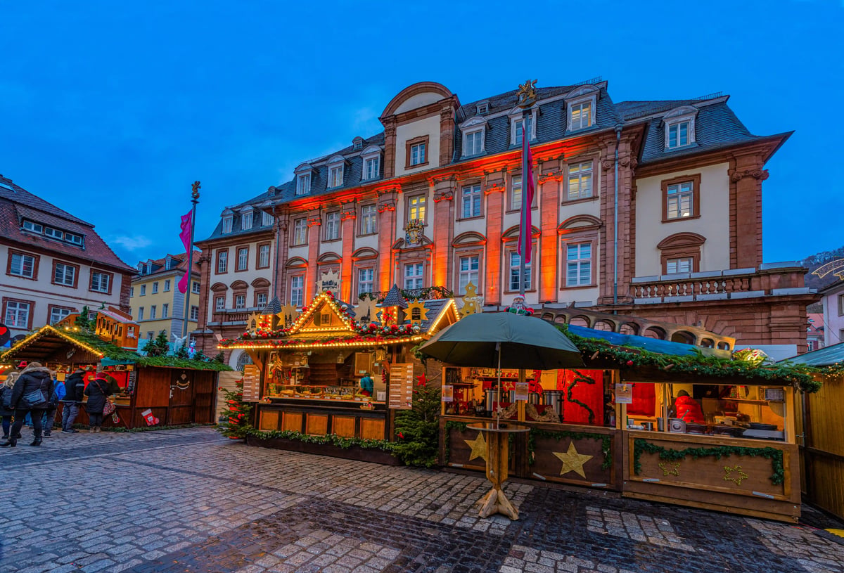 Weihnachtsmarktstände vor dem beleuchteten Rathaus in Stuttgart bei Abenddämmerung