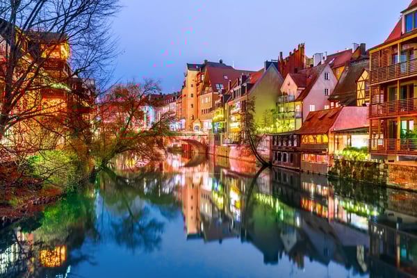 Beleuchtete Altstadt von Nürnberg mit Brücke und Spiegelung im Fluss bei Abenddämmerung
