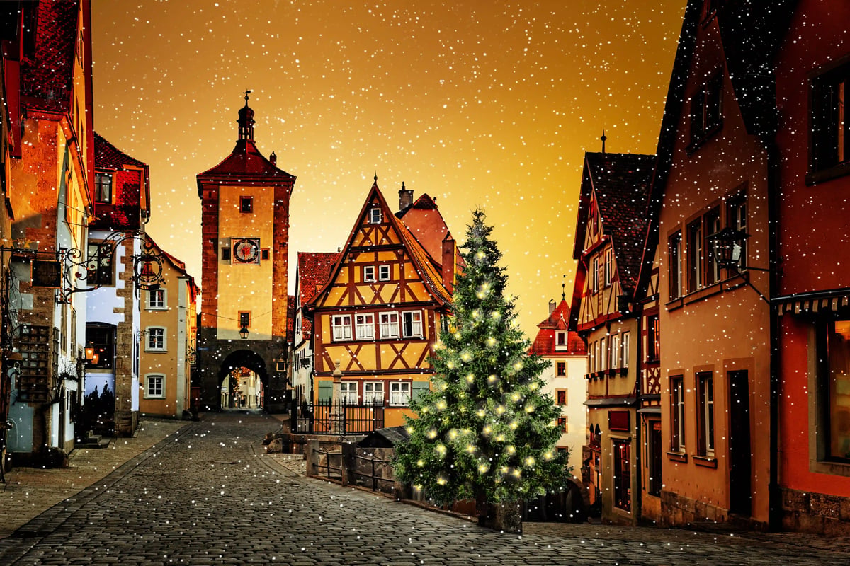 Verschneite Altstadt von Rothenburg ob der Tauber mit Fachwerkhäusern und geschmücktem Weihnachtsbaum