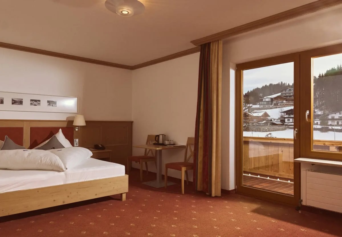 Gemütliches Hotelzimmer mit Doppelbett und Balkon. 
