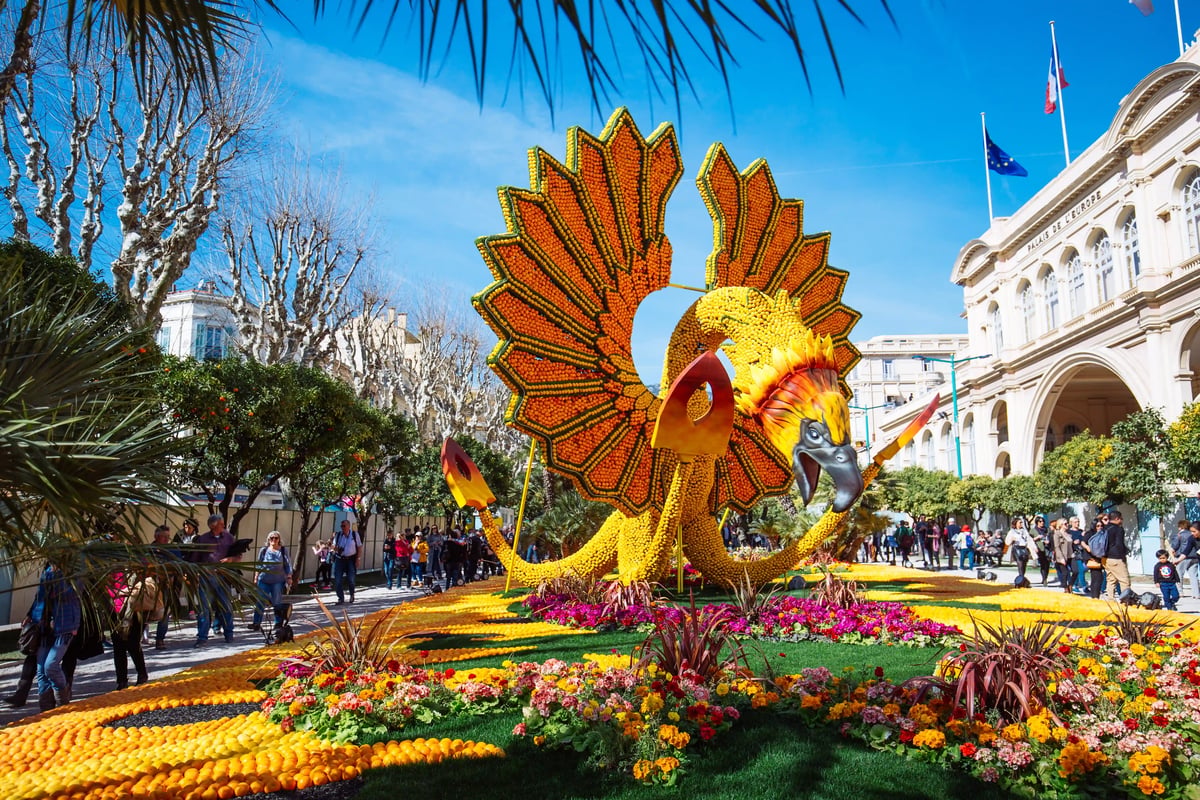 Grosse Skulptur aus Zitronen und Orangen beim Zitronenfest in Menton, umgeben von Blumen und Besuchern