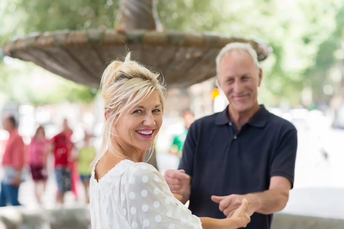Couple heureux dansant tranquillement en plein air devant une fontaine dans un cadre méditerranéen