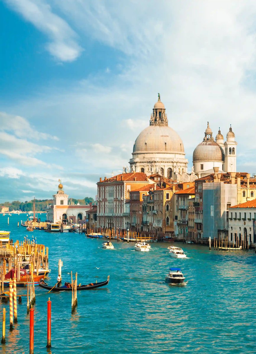 Vue sur le Grand Canal avec une gondole et des bateaux, et au fond le dôme de la basilique Santa Maria della Salute.