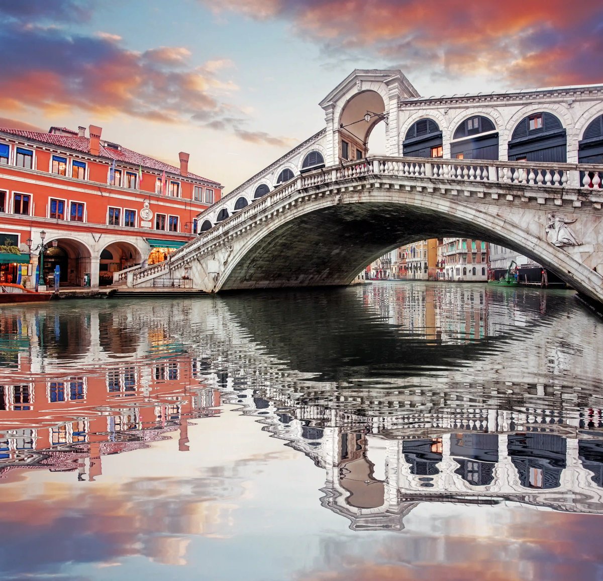 Le pont du Rialto se dresse au-dessus du Grand Canal à la lumière du soir, reflété dans l eau calme entre les palais.