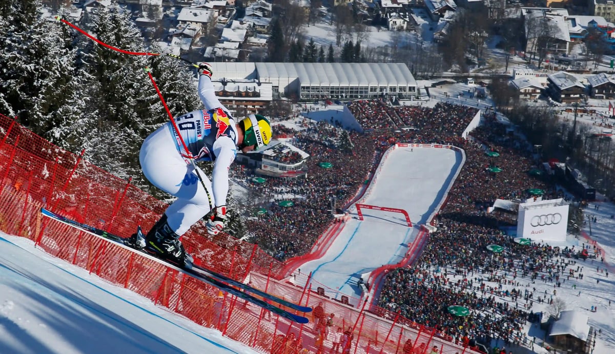 Skirennläufer während des Hahnenkamm Rennens in Kitzbühel mit steiler Piste und Zuschauern im Zielbereich