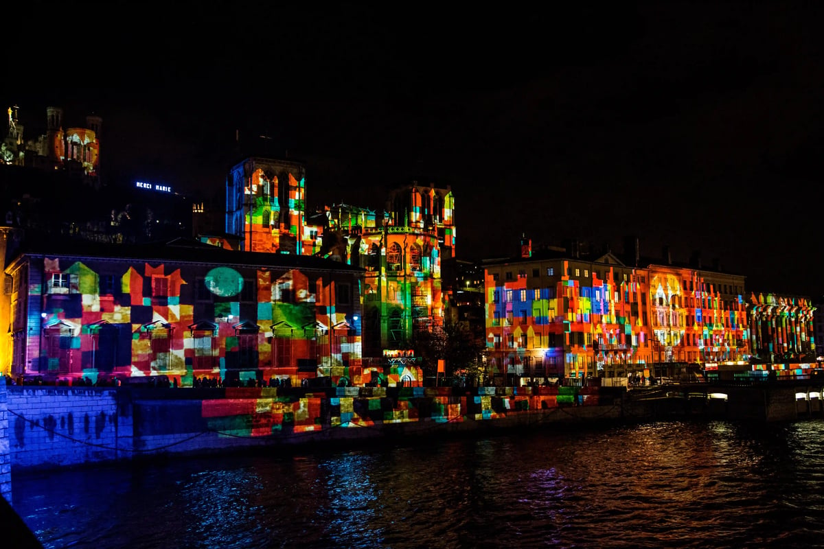 Projections lumineuses colorées sur les façades historiques des quais de Saône lors de la Fête des Lumières à Lyon.