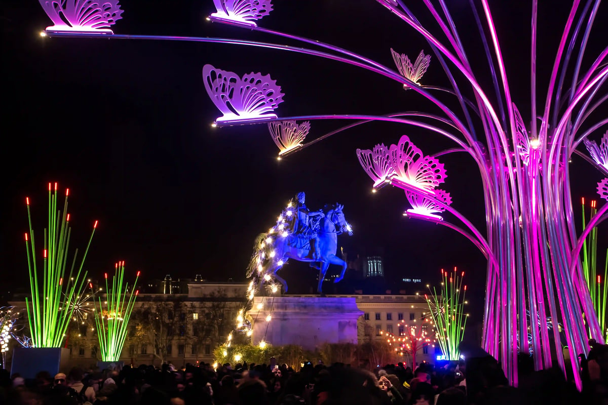 Installation lumineuse de papillons et statue équestre sur la place Bellecour lors de la Fête des Lumières.
