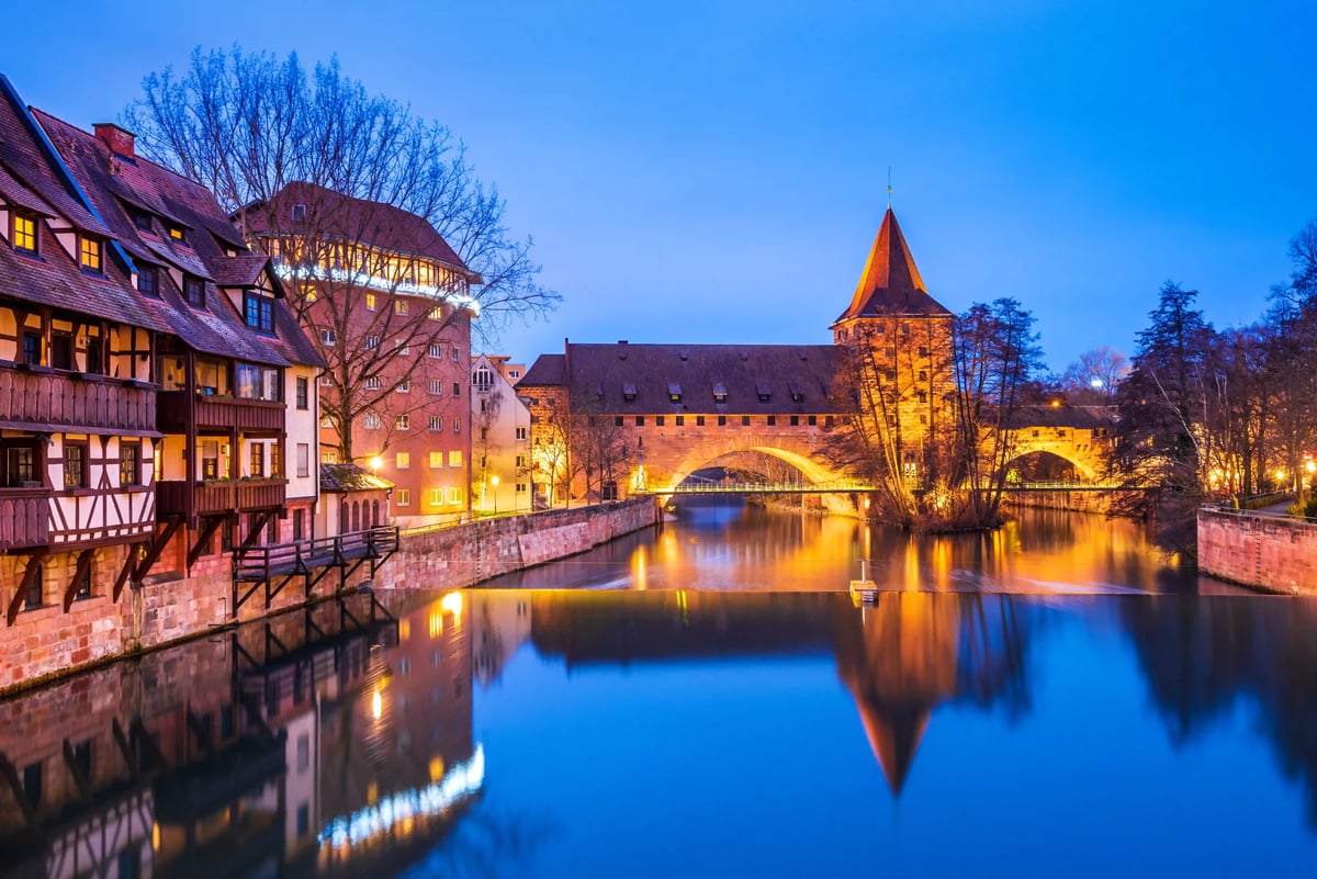 Beleuchtete Nürnberger Altstadt mit Henkersteg und Maxbrücke an der Pegnitz in der Abenddämmerung
