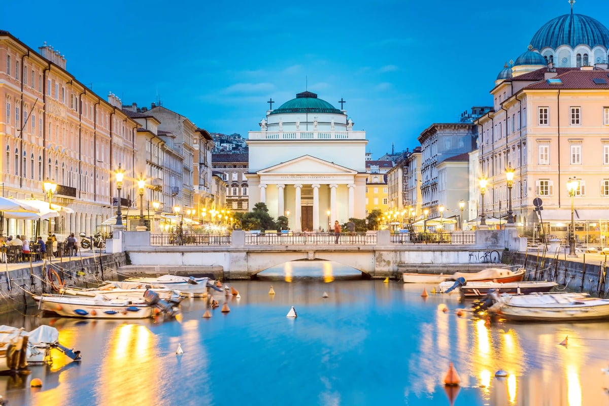 Canal Grande in Triest mit Kirche Sant’Antonio Nuovo, Brücke und Booten in der Abenddämmerung.