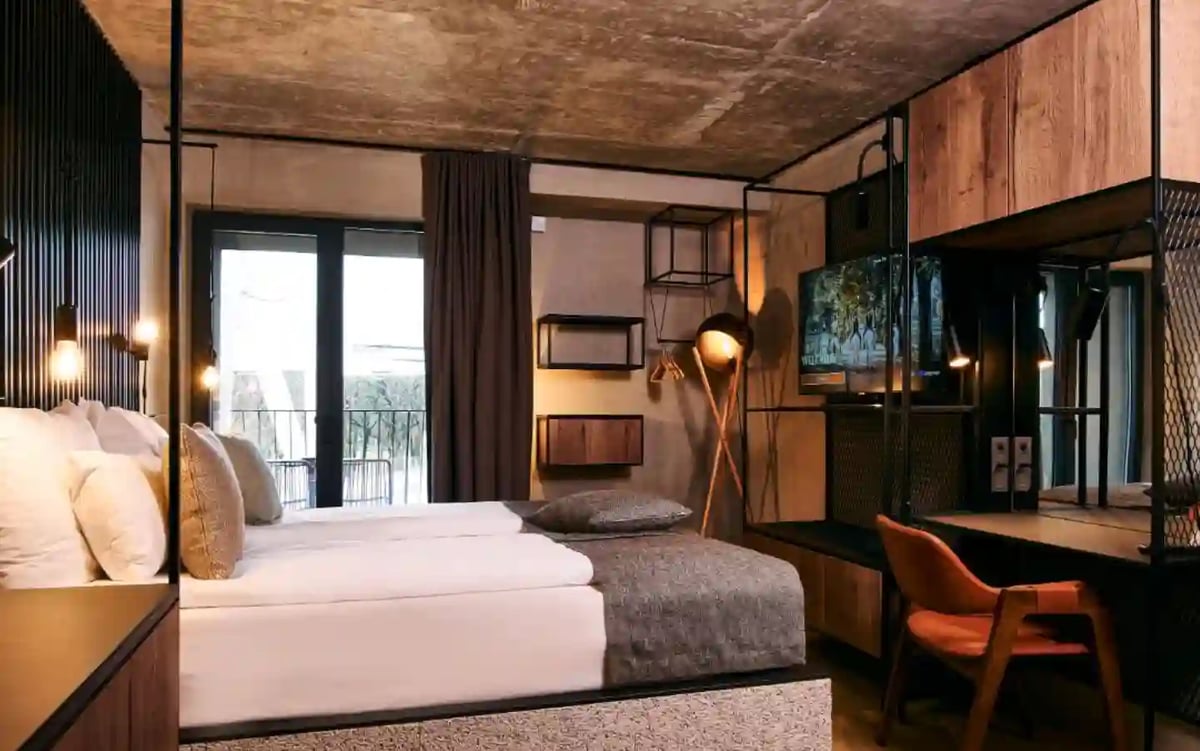 Modernes Hotelzimmer mit Doppelbett, Holzmöbeln und Balkon.