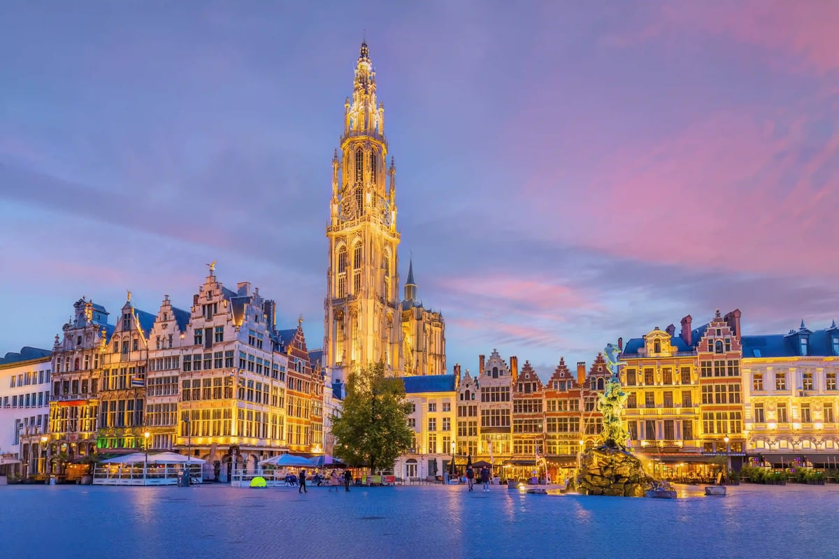 Abendliche Ansicht des Grote Markt in Antwerpen mit prächtigen Zunfthäusern und der imposanten Liebfrauenkathedrale im Hintergrund.
