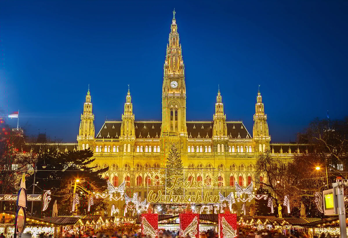 Beleuchtetes Wiener Rathaus mit Weihnachtsmarkt und festlicher Dekoration am Abend