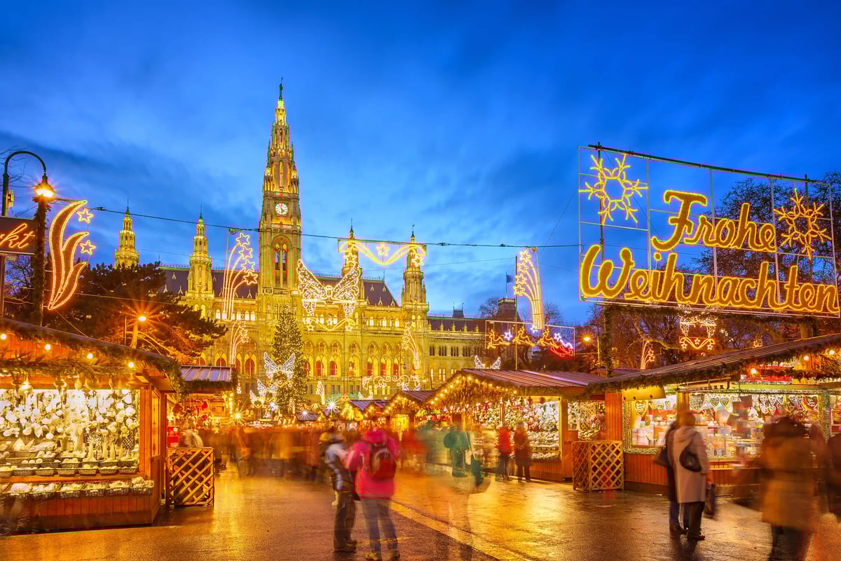 Wiener Christkindlmarkt mit festlich beleuchtetem Rathaus und Besuchern bei Dämmerung