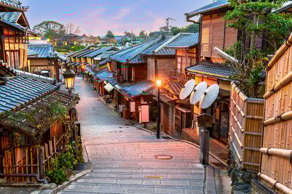 Traditionelle Gasse in Kyoto mit Holzhäusern, Laternen und gepflastertem Weg bei Abendlicht