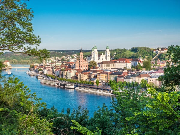 Panoramablick auf die Altstadt von Passau mit Domtürmen und farbigen Häusern entlang der Donau bei klarem Himmel