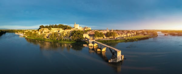 Panorama von Avignon mit Steinbruecke über die Rhone im warmen Abendlicht.