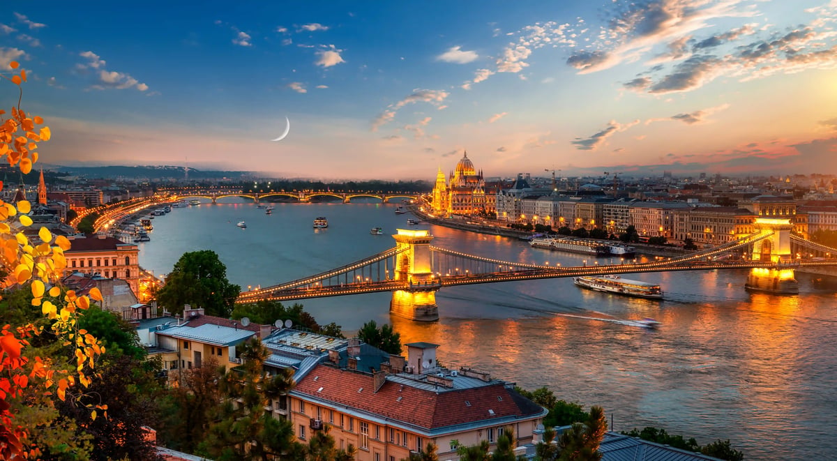 Abendblick auf Budapest mit beleuchteter Kettenbrücke, Donau und Parlamentsgebäude unter farbigem Himmel