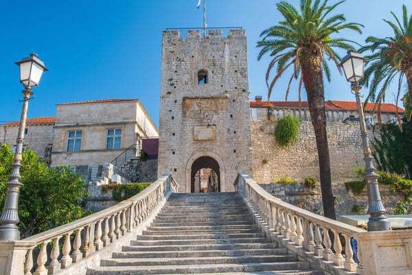 Blick auf die Küstenstadt Korčula mit historischer Bebauung, Booten und grün bewachsenen Hügeln