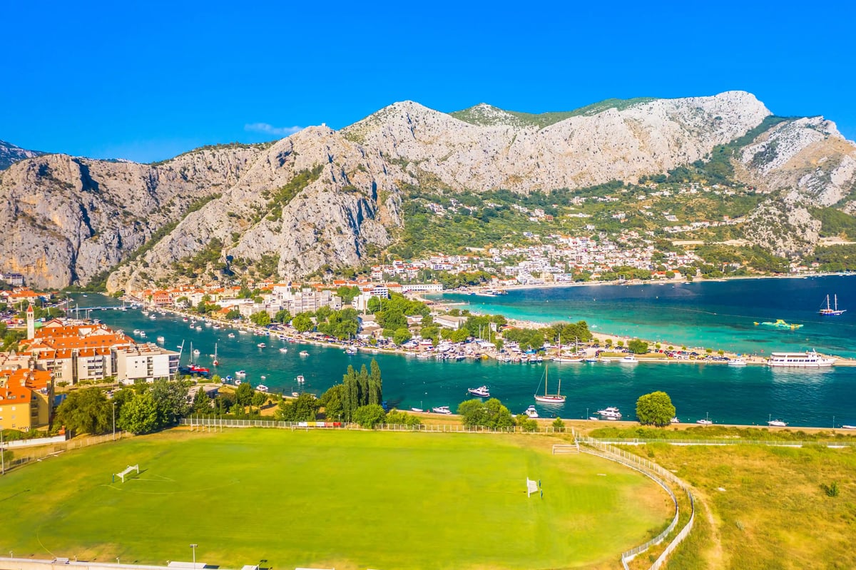 Blick auf Omis mit Flussmündung, Booten und steil aufragenden Felsen im Hintergrund