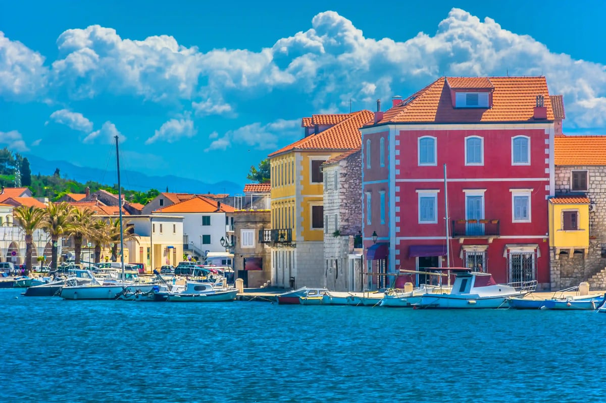 Blick auf die Altstadt von Hvar mit farbigen Häusern, Palmen und Booten am Wasser