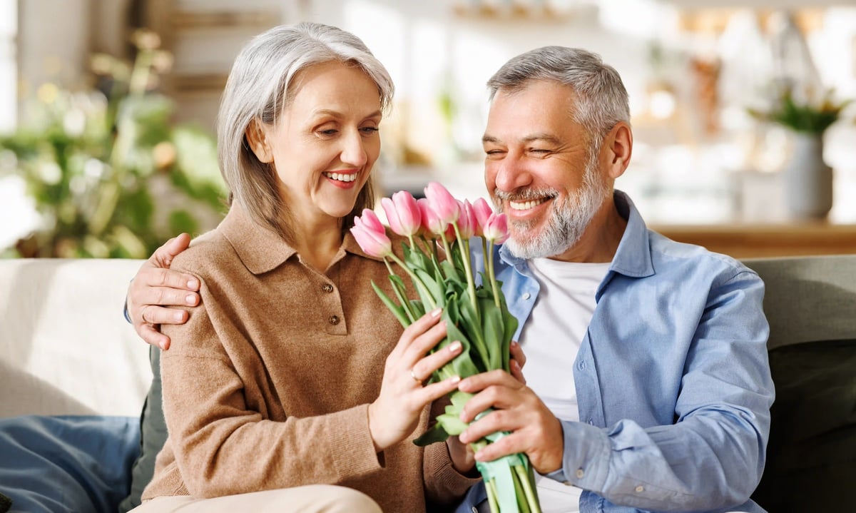 Couple souriant tenant un bouquet de tulipes roses