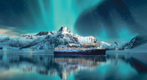 Modernes Kreuzfahrtschiff fährt durch ruhiges arktisches Gewässer vor schneebedeckten Bergen und Polarlichtern