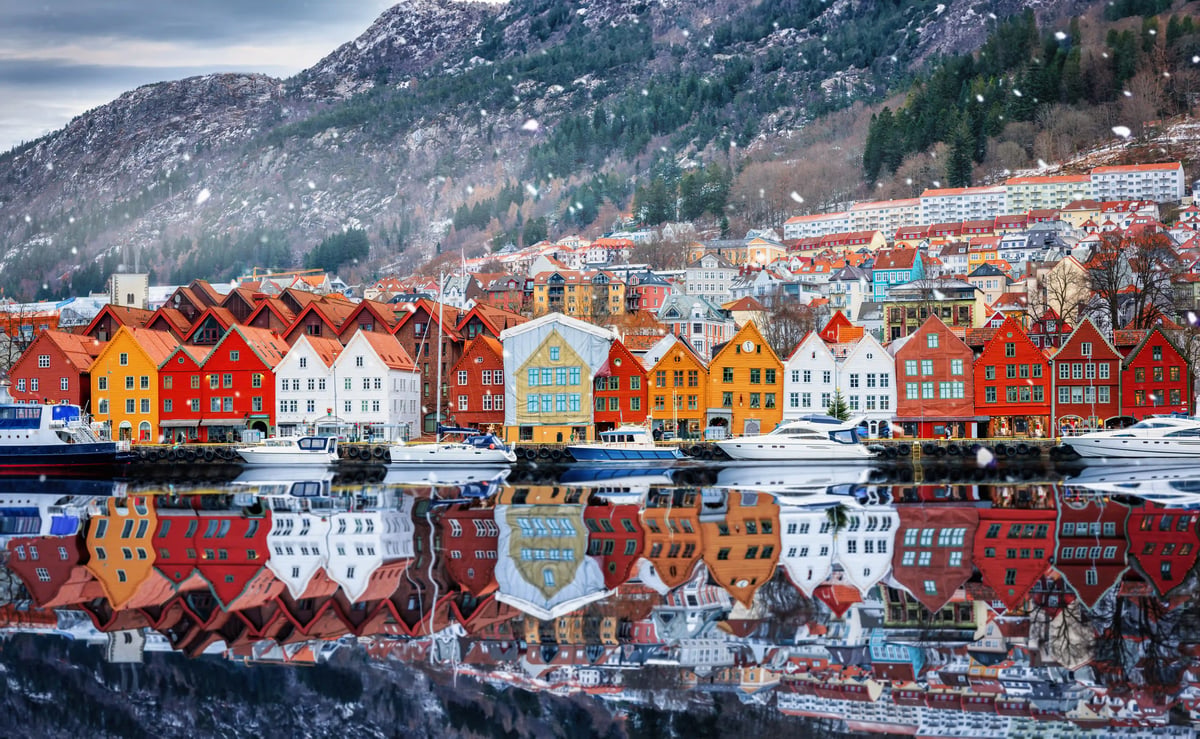 Bunte historische Speicherhäuser im Hafenviertel Bryggen in Bergen mit Booten und Winterlandschaft