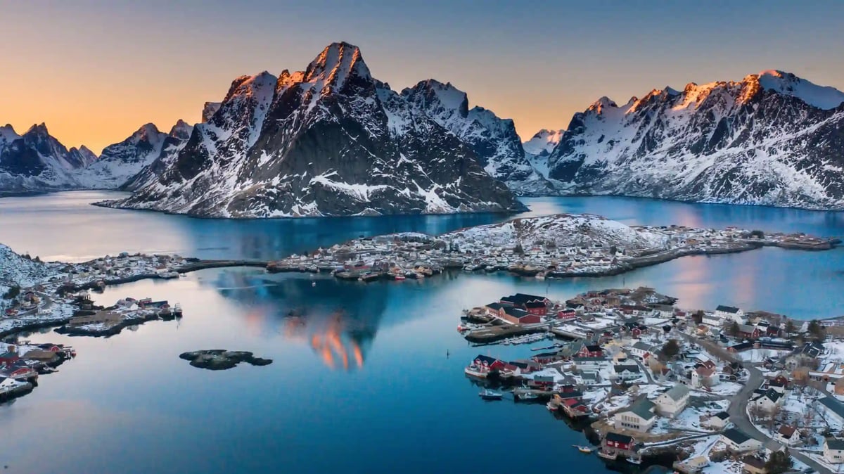 Malerisches Fischerdorf Hamnøy auf den Lofoten mit roten Häusern, Fjord und schneebedeckten Bergen