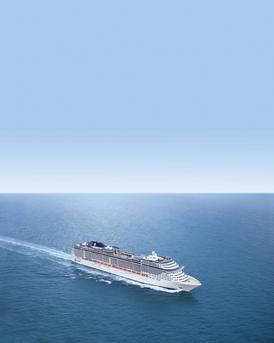 Le grand navire de croisière blanc MSC Preziosa navigue sur la mer bleu profond sous un ciel bleu clair, laissant une traînée d'écume blanche dans l'eau.