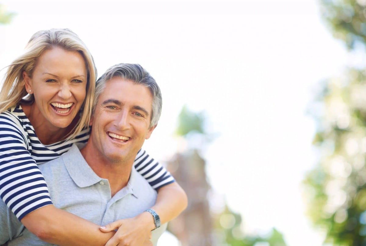 Un couple riant en plein air sur un fond vert flou.