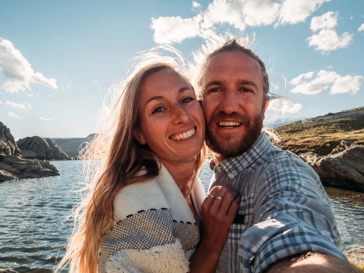 Glückliches Paar macht ein Selfie an felsiger Küste mit Meer im Hintergrund