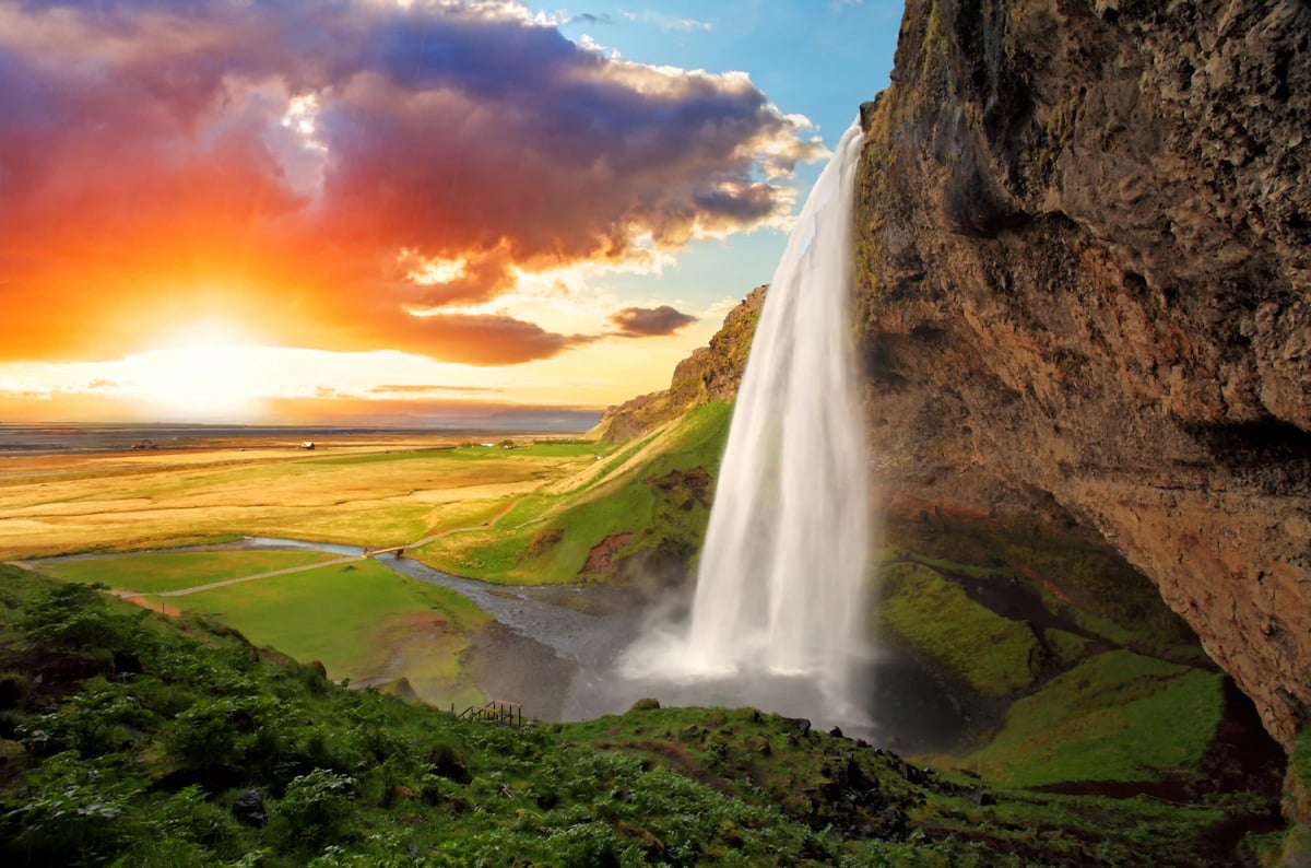 Majestätischer Wasserfall in Island vor weiter Landschaft und Abendhimmel
