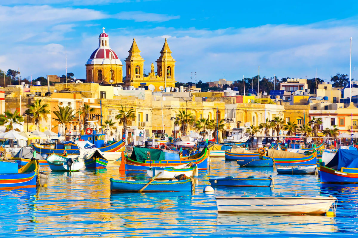 Bunter Hafen auf Malta mit traditionellen Booten, Palmen und historischer Architektur