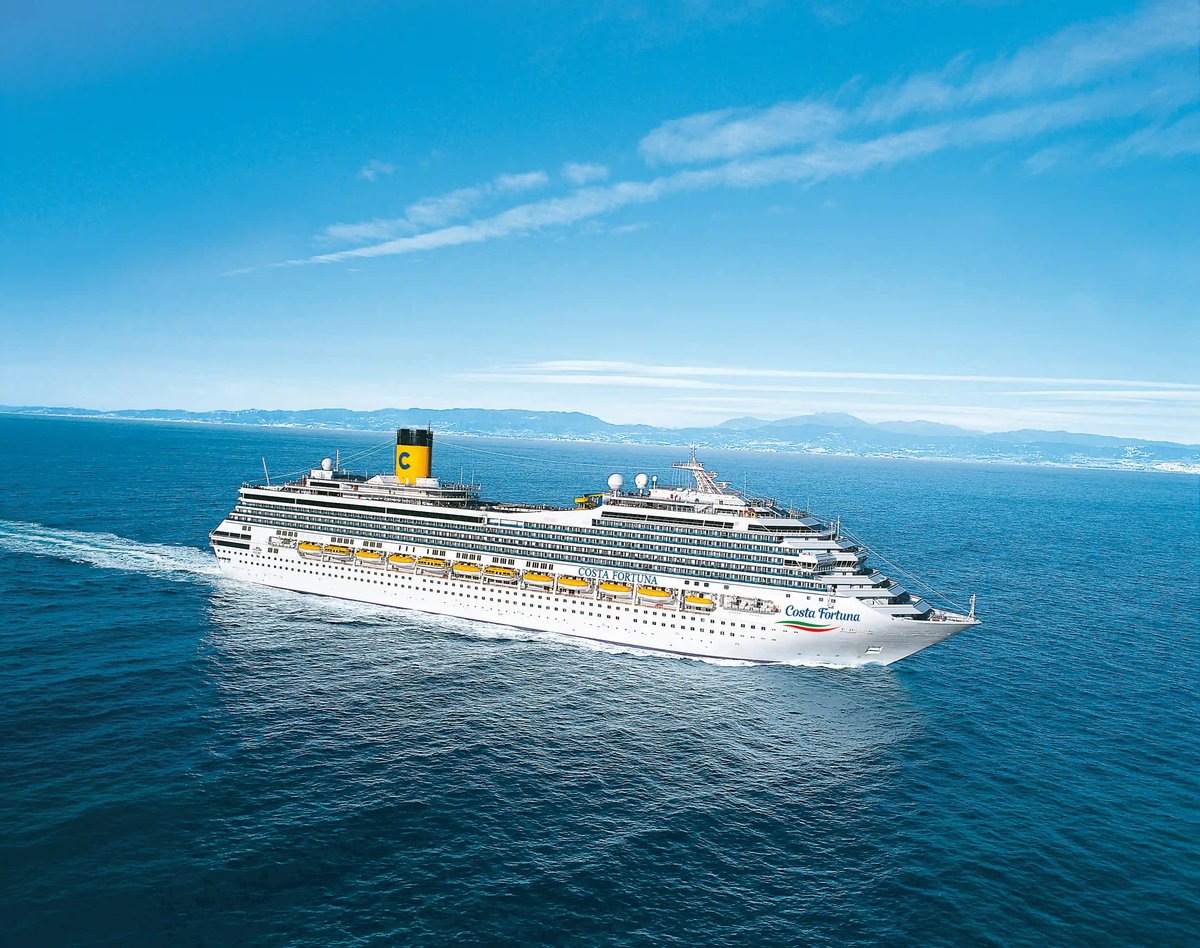 Grosses Kreuzfahrtschiff Costa Fortuna fährt bei ruhigem Wetter auf blauem Meer, im Hintergrund Küstenlinie und Berge