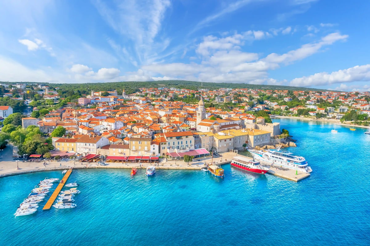 Blick auf die Altstadt von Krk mit roten Dächern, Hafen und türkisblauem Meer