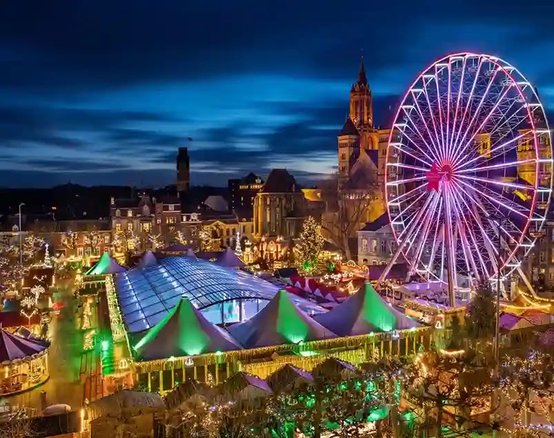 Grosser Weihnachtsmarkt in Maastricht mit Riesenrad, festlicher Beleuchtung und Marktständen bei Nacht