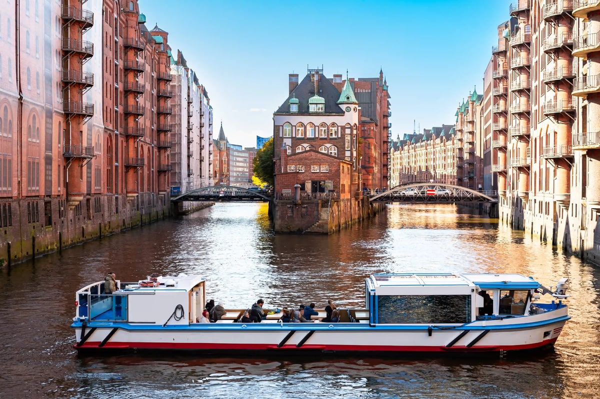 Ausflugsboot auf einem Kanal zwischen den historischen Backsteingebäuden der Speicherstadt in Hamburg