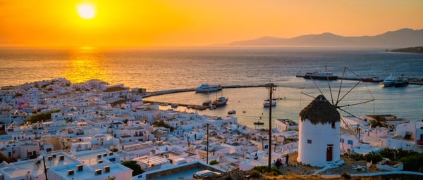 Weisse Häuser von Mykonos am Meer bei goldenem Sonnenuntergang