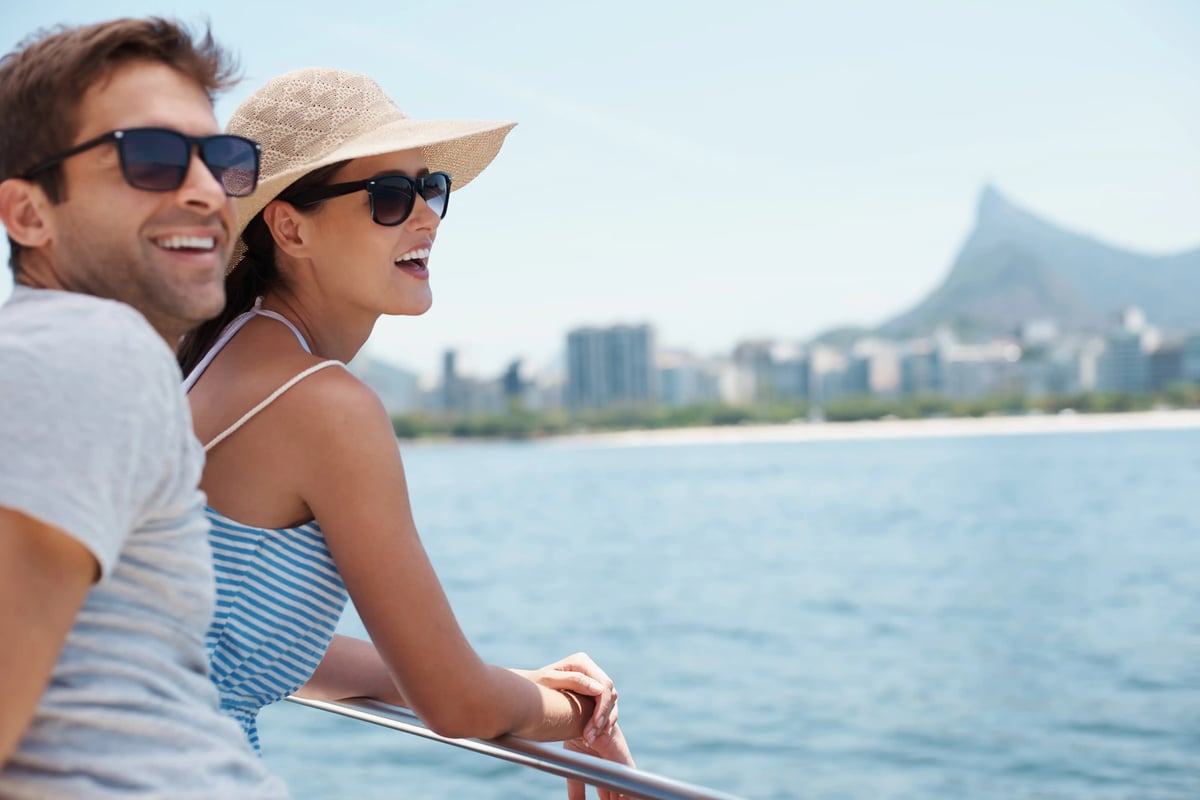 Couple avec lunettes de soleil regardant une ville côtière depuis un bateau