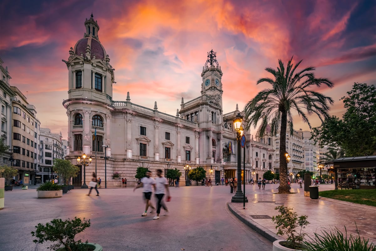 Hôtel de ville historique à Valence au coucher du soleil avec palmiers et passants sur la place