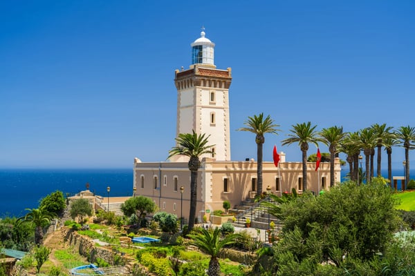 Leuchtturm nahe Tanger mit Palmen und gepflegter Gartenanlage auf einer Klippe mit Blick auf das tiefblaue Meer
