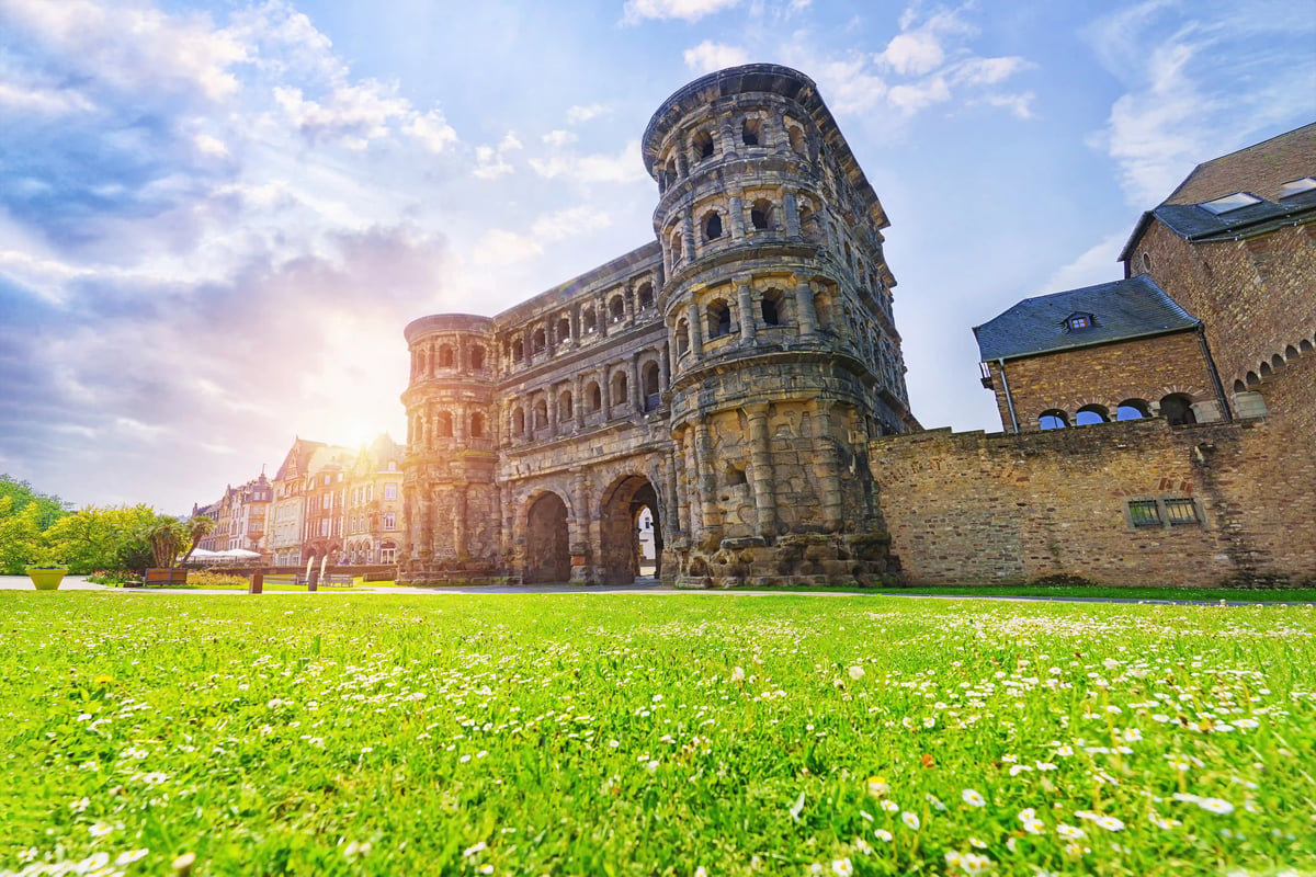 La Porta Nigra de Trèves, monument romain emblématique d’Allemagne, se dresse devant une pelouse verdoyante sous un ciel lumineux