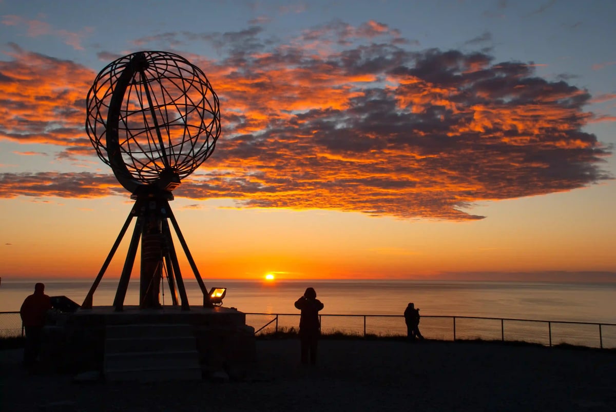 Nordkap mit Metallglobus bei Sonnenuntergang über dem Meer