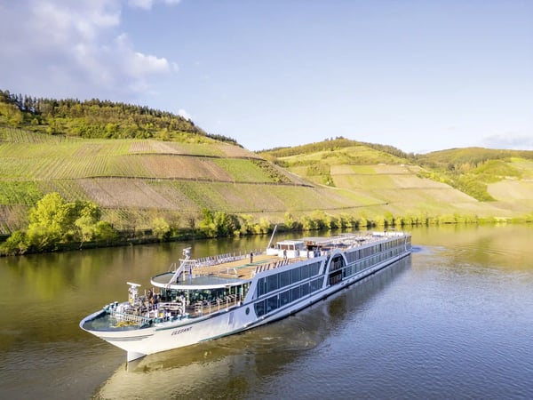 Flussschiff MS Elegant fährt auf einem breiten Fluss durch Weinberge und grüne Hügellandschaft.