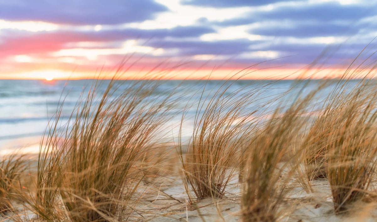 Sanddünen an der Ostseeküste bei Sonnenuntergang mit Blick auf Meer und Himmel