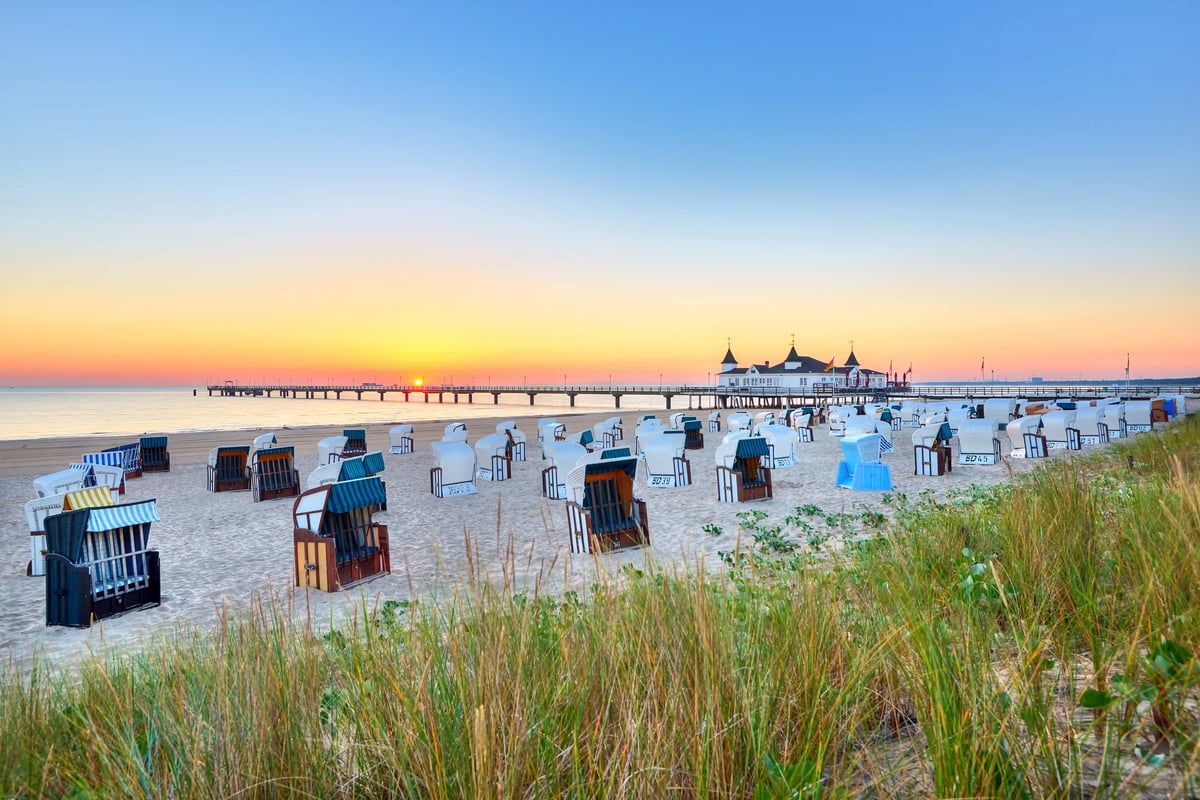 Strand mit Strandkörben und Seebrücke bei Sonnenuntergang an der Ostsee