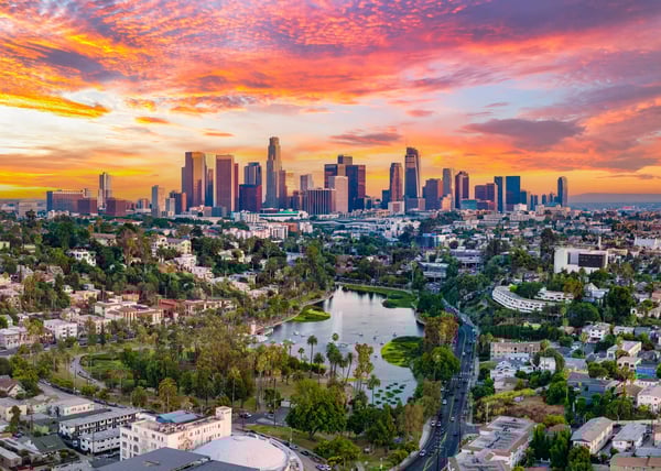 Skyline von Los Angeles bei Sonnenuntergang mit Hochhäusern und Park im Vordergrund