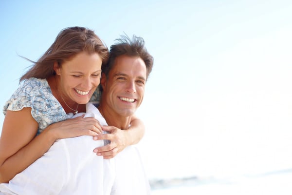 Glückliches Paar lächelt am Strand bei hellem Tageslicht