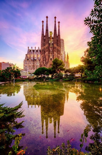 Sagrada Familia in Barcelona mit Spiegelung im Wasser und farbigem Abendhimmel