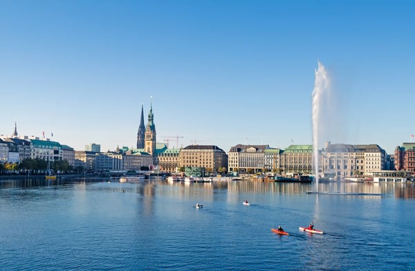 Blick über die Hamburger Binnenalster mit Fontäne, historischen Gebäuden und Booten auf dem Wasser